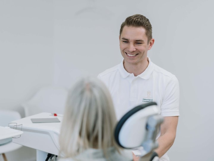 Zahnarzt berät Patientin im Behandlungszimmer