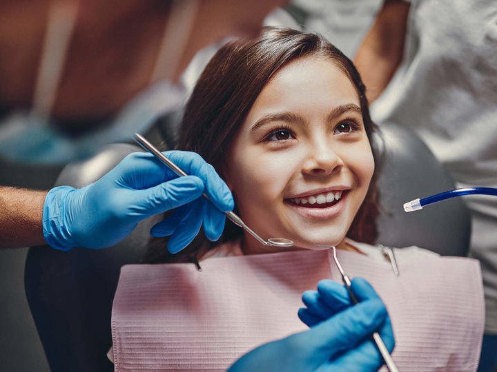 Mädchen wird beim Zahnarzt mit Instrumenten behandelt